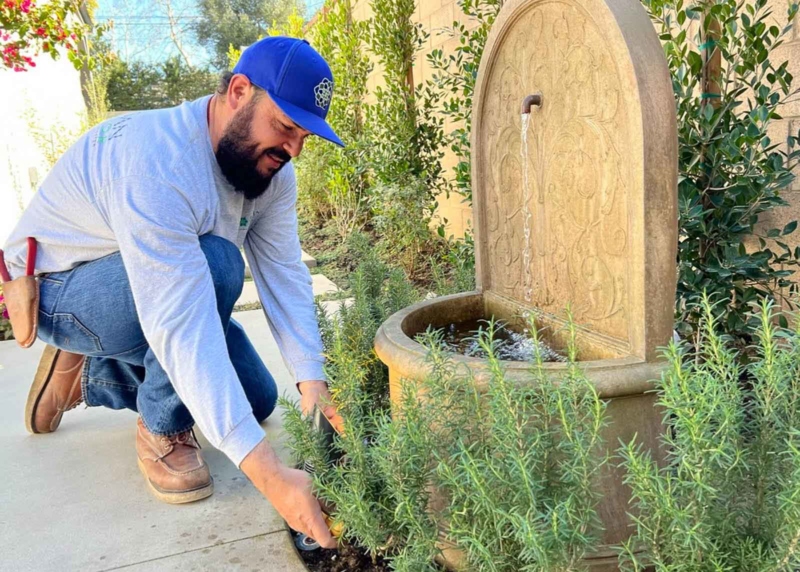 Landscaper crouched near a fountain and smiling