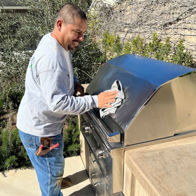 Landscaper cleaning a grill and smiling