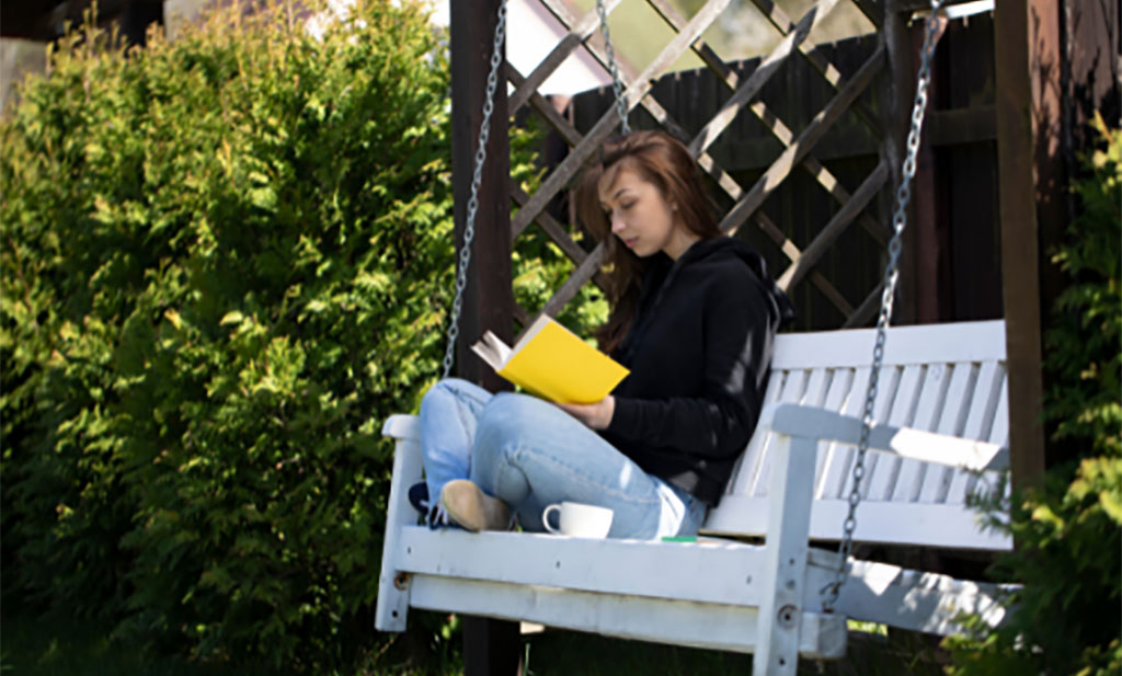 Woman reading a book on a bench swing